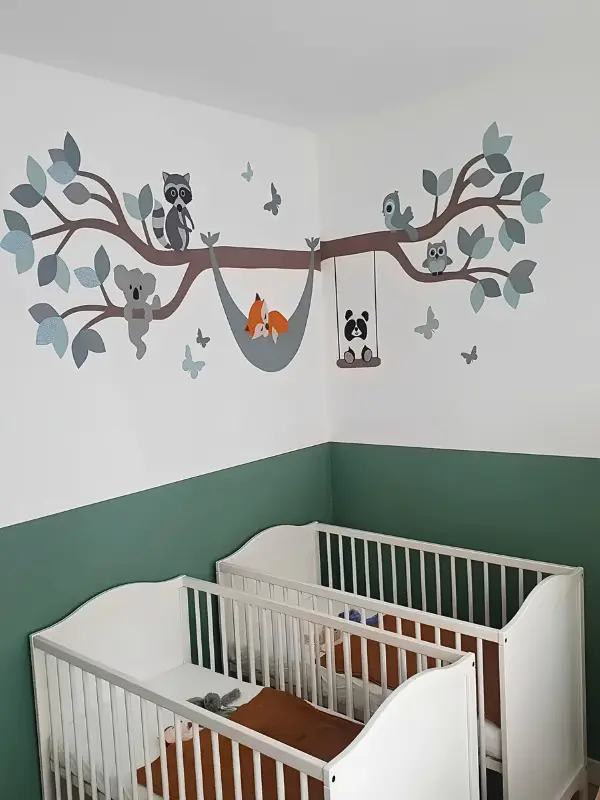 Oudgroene babykamer met behangsticker tak met dieren boven het ledikant